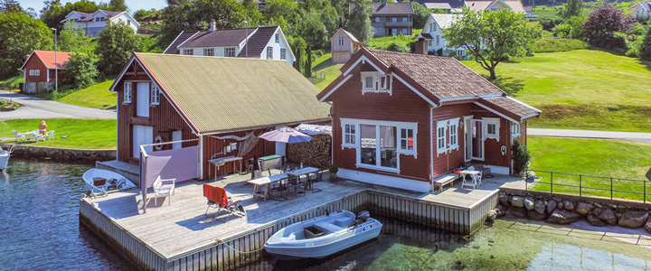 Blick von oben auf ein landestypisches Novasol Ferienhaus direkt am Wasser gelegen mit eigener Terrasse und Bootsanlegeplatz.