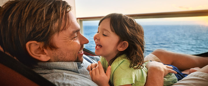 Ausgelassene Familienstimmung: Vater und Kind lächeln sich entgegen, auf einem Balkon der AIDAnova.