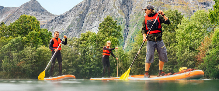 Drei Leute beim Standup-Paddeling durch die märchenhaften Fjörde Norwegens und die abwechslungsreiche Natur.