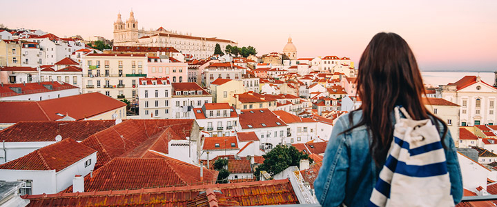 Junge Frau mit AIDA Rücksack, nimmt unsern Blick mit über die Altstadt von Barcelona in Abendlicht-Stimmung.